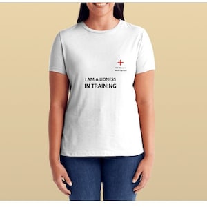 Puede incluir: Camiseta blanca con una cruz roja y el texto "FIFA Women's World Cup 2023" y "I AM A LIONESS IN TRAINING".