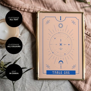 May include: A gold-framed table number card with a peach background and blue celestial design. The number "1" and the text "TABLE ONE" are in blue.