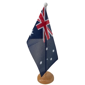 May include: A small Australian flag on a wooden desk stand. The flag is blue with a white star pattern and a red Union Jack in the top left corner.