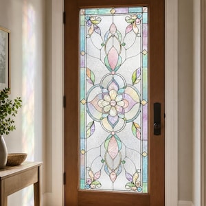 Può includere: Una porta in legno dotata di un ampio pannello rettangolare in vetro colorato con un motivo floreale centrale. Il vetro presenta tonalità pastello di rosa, blu, verde e viola all'interno di una cornice geometrica in piombo e metallo nero.