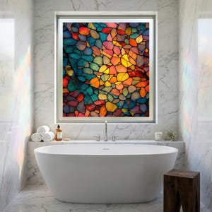 May include: A modern bathroom with a white oval bathtub and a large window featuring a colorful abstract stained-glass design. The artwork showcases a mosaic of vibrant colors, including blue, orange, yellow, and red. The room has marble walls and a wooden stool.