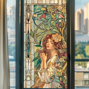 May include: Stained glass window depicting a woman with auburn hair and floral adornments. The Art Nouveau design uses flowing lines and a colour scheme of greens, yellows, and blues. The woman is wearing a white dress.