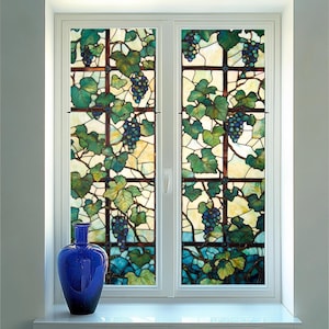 Puede incluir: Una ventana de vidriera con un diseño de vid. La ventana está dividida en dos secciones, cada una con un patrón diferente de hojas y uvas. El vidrio es una mezcla de verde, azul y amarillo.