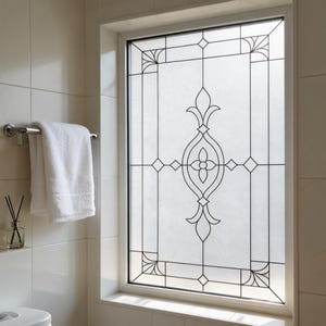 May include: A rectangular window featuring a frosted glass surface with a black leaded geometric pattern. The design includes a central floral motif with symmetrical lines, corner fan details, and thin borders, creating a semi-opaque privacy screen.