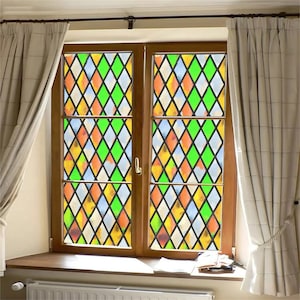 以下が含まれることがあります： 緑、オレンジ、黄色、白のダイヤモンドパターンが施されたステンドグラスのデザインの窓です。