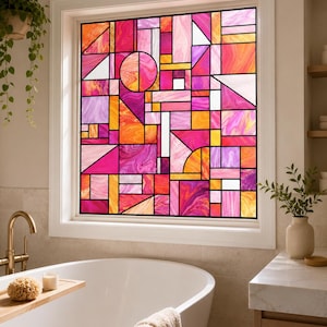May include: A window film featuring a geometric stained glass pattern with a vibrant colour palette of pink, magenta, orange, and yellow. The design consists of various shapes including triangles, rectangles, and a circle, all outlined in black lines.