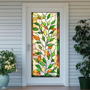 Puede incluir: Un film de ventana de vidrio emplomado con un árbol estilizado con hojas verdes y naranjas. La película está instalada en una puerta blanca.