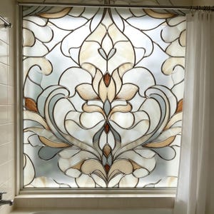 Könnte beinhalten: Ein Fensterpaneel mit einem Buntglasdesign in einem symmetrischen Damastmuster. Das Glas besteht aus durchscheinenden weißen, cremefarbenen und hellbraunen Segmenten, die durch dünne Metallstege verbunden sind und ein florales Motiv bilden.