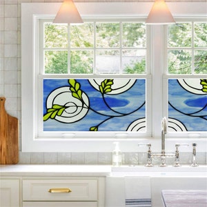 K&ouml;nnte beinhalten: Eine Bleiglas-Fensterfolie mit blauem Hintergrund und gr&uuml;nen Bl&auml;ttern. Die Folie zeigt ein sich wiederholendes Muster aus Kreisen und Spiralen.