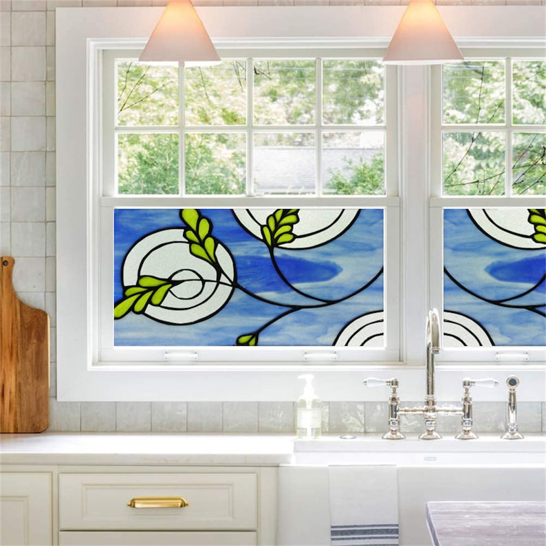 K&ouml;nnte beinhalten: Eine Bleiglas-Fensterfolie mit blauem Hintergrund und gr&uuml;nen Bl&auml;ttern. Die Folie zeigt ein sich wiederholendes Muster aus Kreisen und Spiralen.