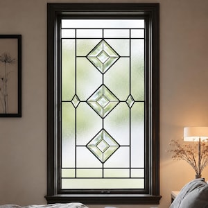 Op de afbeelding: Een rechthoekig raam met een donkerbruin kozijn voorzien van een decoratief glas-in-loodpatroon. Het glas heeft een gematteerde textuur en bevat drie centraal verticaal geplaatste ruitvormige panelen, geflankeerd door kleinere ruitaccenten.