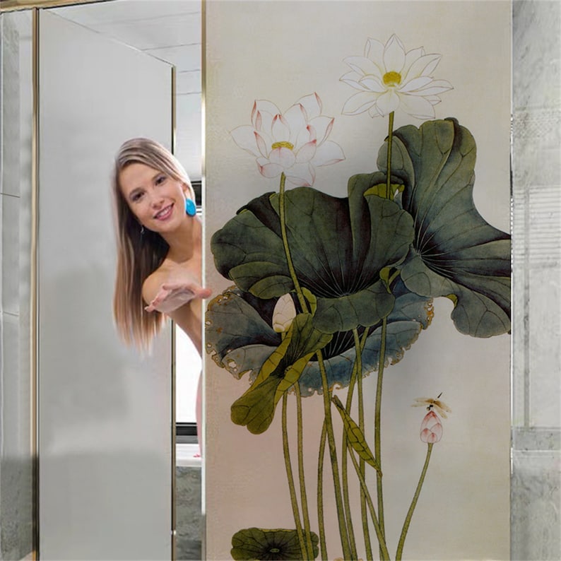 K&ouml;nnte beinhalten: Eine gefrostete Glast&uuml;r f&uuml;r die Dusche mit einem dekorativen Blumendesign mit wei&szlig;en und rosa Lotusblumen und gr&uuml;nen Bl&auml;ttern.