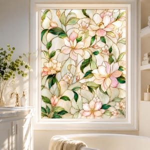 Puede incluir: Una película para ventana con efecto de vidriera que presenta un patrón floral repetitivo de flores de color rosa claro y hojas verdes delineadas con finas líneas doradas. El diseño cubre toda la superficie rectangular con motivos botánicos.