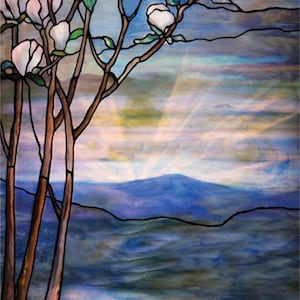 May include: A stained glass window depicting a landscape with a mountain range in the background, a lake in the foreground, and a tree with white blossoms in the foreground. The sky is blue with white clouds and rays of light shining through.