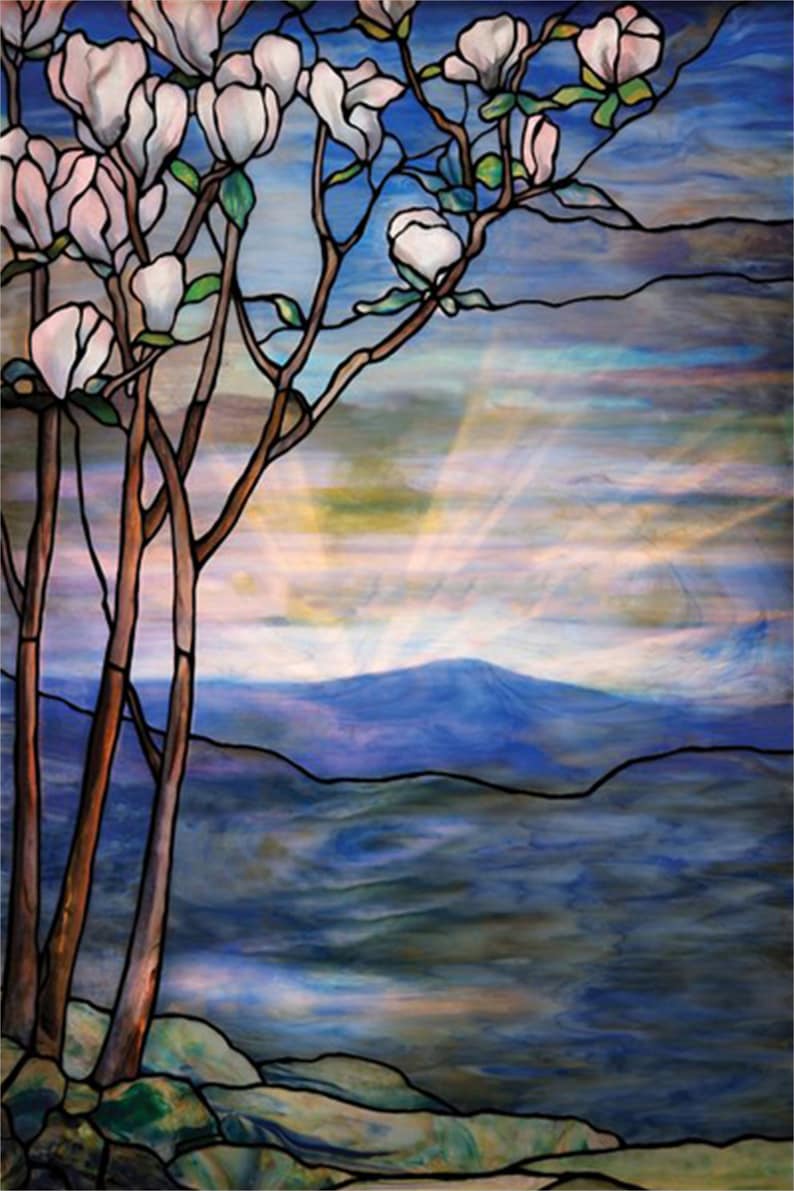 May include: A stained glass window depicting a landscape with a mountain range in the background, a lake in the foreground, and a tree with white blossoms in the foreground. The sky is blue with white clouds and rays of light shining through.