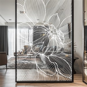 May include: A white line art design of a flower on a clear glass panel. The panel is framed in black metal.