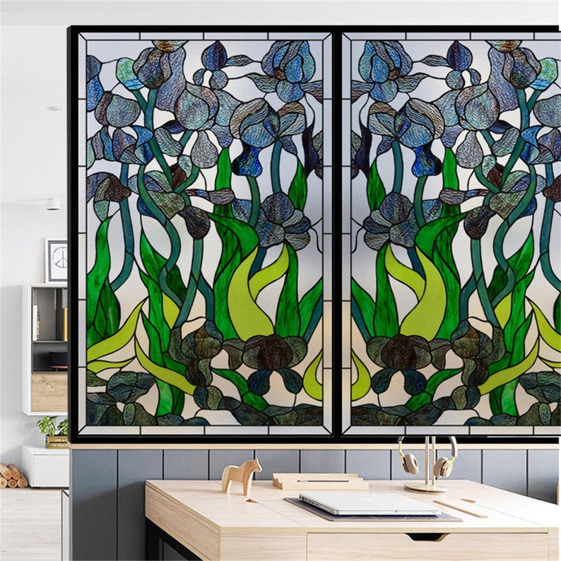 K&ouml;nnte beinhalten: Eine Fensterfolie im Stil eines Buntglasfensters mit einem floralen Design aus blauen Iris und gr&uuml;nen Bl&auml;ttern. Die Folie ist so konzipiert, dass sie wie ein traditionelles Buntglasfenster aussieht.