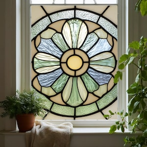 May include: A stained glass window with a floral design. The window features a central yellow circle surrounded by petal-shaped sections in shades of green, blue, and cream, outlined in black. The window is set in a white frame.