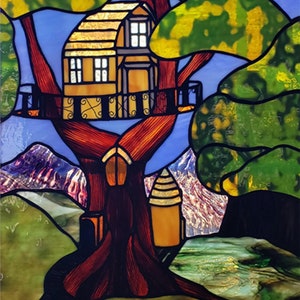 May include: A stained glass window featuring a tree house nestled in a large tree with a brown trunk and green foliage. The tree house is yellow with brown detailing and has two windows. The background shows a blue sky with mountains and a river.