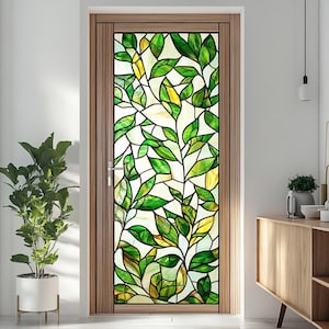Pode incluir: Um filme de janela de vitral com um design de folhas verdes e amarelas. O filme é aplicado em uma porta com uma moldura de madeira.