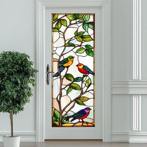 Könnte beinhalten: Ein Buntglas-Fensteraufkleber mit einem farbenfrohen Baum, auf dem drei Vögel auf den Ästen sitzen. Die Vögel sind rot, blau, grün und gelb.
