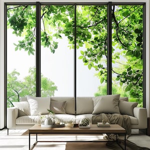 Könnte beinhalten: Ein weißes Sofa mit beigefarbenen Kissen steht vor einem großen Fenster mit Blick auf grüne Bäume und Blätter. Ein Holz-Couchtisch steht vor dem Sofa.