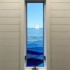 May include: A rectangular window with a white frame and a stained glass design depicting a sailboat on the ocean. The glass features shades of blue, with a white sailboat on the horizon. The window is set in a white paneled wall.