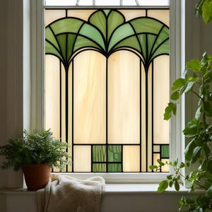 Op de afbeelding: Gebrandschilderd glasraam met een groen en crèmekleurig ontwerp. Het ontwerp toont gestileerde palmbladeren aan de bovenkant en geometrische vormen aan de onderkant, allemaal omlijnd in zwart. Het raam zit in een wit frame.