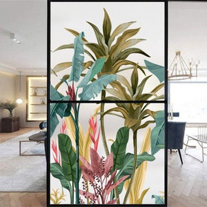 May include: A window film featuring a tropical design with large green leaves, yellow flowers, and pink flowers. The design is printed on a clear film that can be applied to any window.