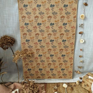 Puede incluir: Una hoja rectangular de papel de regalo color canela con un patr&oacute;n repetitivo de peque&ntilde;as flores estilizadas en tonos naranja apagado, azul polvoriento y rosa suave. El dise&ntilde;o floral est&aacute; dispuesto en filas verticales por todo el papel.