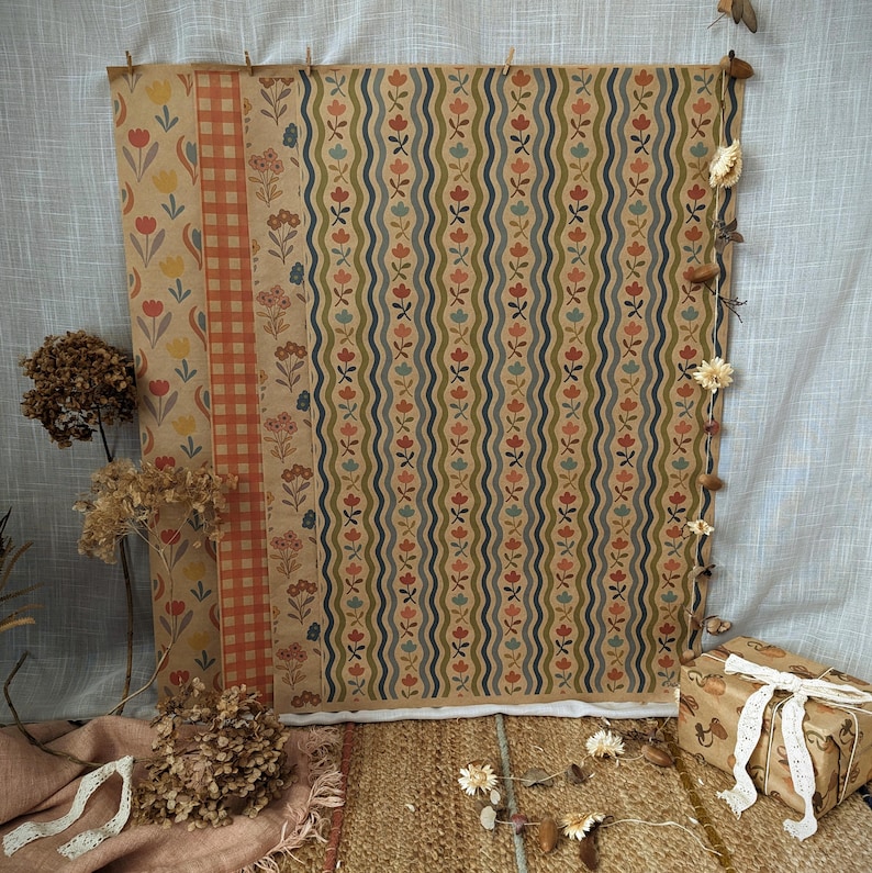 Puede incluir: Una hoja grande de papel de regalo con un patr&oacute;n vertical de l&iacute;neas onduladas intercaladas con peque&ntilde;as flores rojas, azules y amarillas. El dise&ntilde;o incluye una secci&oacute;n con cuadros vichy rojos y blancos y un panel de flores.