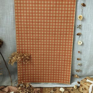Puede incluir: Un p&oacute;ster rectangular con un patr&oacute;n repetitivo de cuadros vichy en naranja y beige. El papel tiene un borde fino y se muestra verticalmente. El dise&ntilde;o consiste en una cuadr&iacute;cula uniforme de peque&ntilde;os cuadrados en tonos alternos.