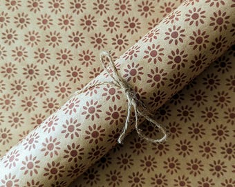 May include: A roll of brown wrapping paper with a repeating pattern of small, red, stylized sunbursts.