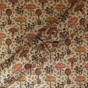 May include: Brown wrapping paper with a repeating pattern of orange and brown mushrooms with white accents. The paper is rolled up and tied with twine.