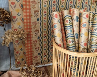 May include: A collection of rolled wrapping paper sheets featuring various patterns including orange gingham, floral motifs, and wavy lines with blue, red, and yellow flowers, all stored in a cylindrical bamboo basket with vertical slats.