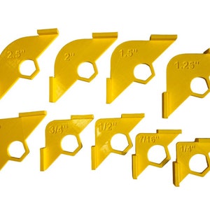 May include: Set of nine yellow plastic corner tile spacers with different sized holes. The sizes are 2.5", 2", 1.5", 1.25", 1", 3/4", 1/2", 7/16", and 1/4".