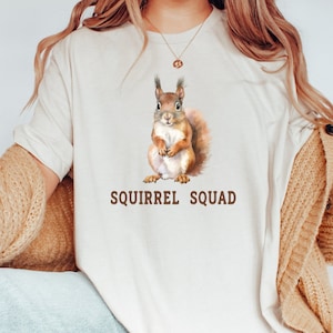 May include: A white t-shirt with a watercolor illustration of a squirrel and the text "Squirrel Squad".