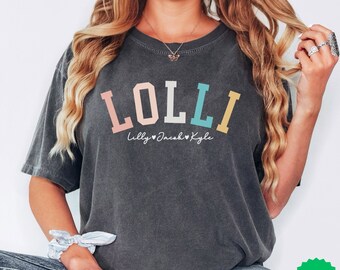 May include: A dark gray t-shirt with the word "LOLLI" in rainbow colors. The text "Lilly Jacob Kyle" is written below the word "LOLLI" in a smaller font.