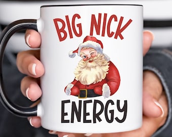 May include: White ceramic mug with a black handle. The mug has a cartoon image of Santa Claus winking and the text "BIG NICK ENERGY" in black.