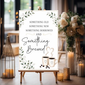 May include: A rectangular white sign on a wooden easel featuring green leaf illustrations in the corners and the text "SOMETHING OLD SOMETHING NEW SOMETHING BORROWED AND Something Brewed" above two coffee mugs with heart-shaped steam and coffee beans.