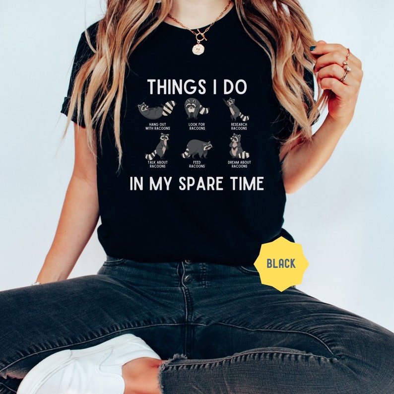 May include: Black t-shirt with the text "THINGS I DO" and illustrations of raccoons doing various activities. The text below the illustrations reads "IN MY SPARE TIME".