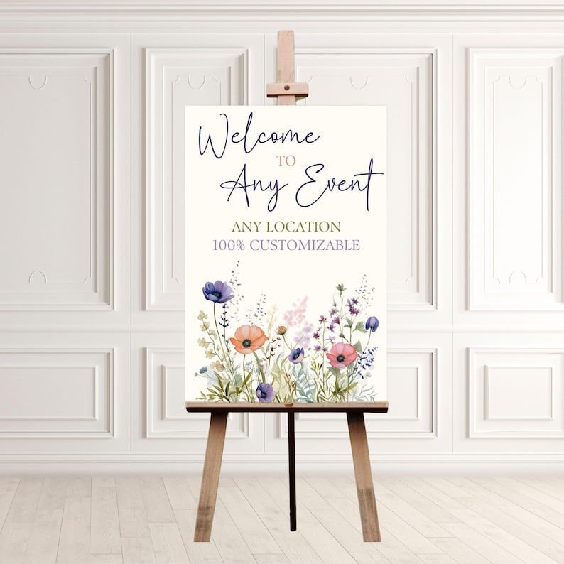 Puede incluir: Se&ntilde;al de bienvenida a cualquier evento con un dise&ntilde;o floral de acuarela con flores rosas, moradas y azules. La se&ntilde;al est&aacute; en un caballete y dice "Bienvenido a cualquier evento" con el texto "Cualquier ubicaci&oacute;n 100% personalizable" debajo.