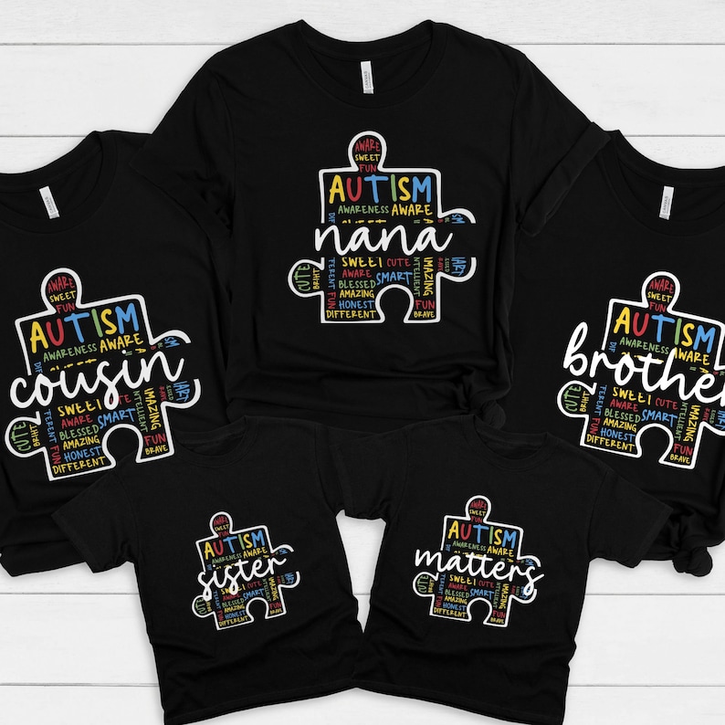 May include: Five black t-shirts with a white puzzle piece design. The puzzle piece is filled with colorful text that says "Autism Awareness" and includes words like "sweet", "cute", "amazing", "brave", "honest", and "different". The shirts have different text on them, including "nana", "cousin", "sister", "brother", and "matters".