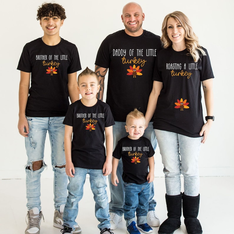 May include: A family of five wearing black t-shirts with Thanksgiving-themed text and a turkey graphic. The shirts say "Brother of the Little Turkey", "Daddy of the Little Turkey", "Roasting a Little Turkey", and "Brother of the Little Turkey".