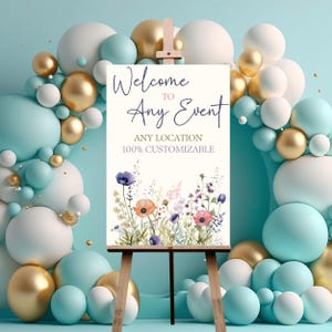 Puede incluir: Se&ntilde;al de bienvenida a cualquier evento con un dise&ntilde;o floral. La se&ntilde;al est&aacute; en un caballete y rodeada de globos en tonos azules, blancos y dorados.
