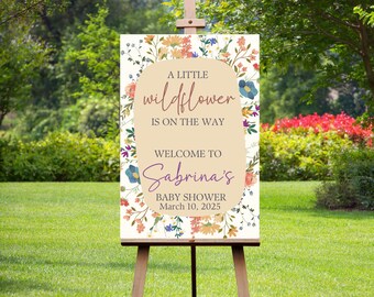 May include: A floral baby shower welcome sign with the text "A little wildflower is on the way. Welcome to Sabrina's Baby Shower March 10, 2025".