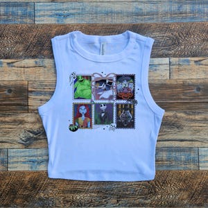 May include: White sleeveless crop top featuring a colorful graphic of postage stamps with characters from The Nightmare Before Christmas. The stamps include images of characters like Jack Skellington, Sally, and Oogie Boogie.