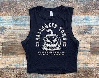 May include: Black sleeveless crop top with a white graphic of a pumpkin with a scary face and the text "Halloween Town 1996" and "Where being normal is vastly overrated".