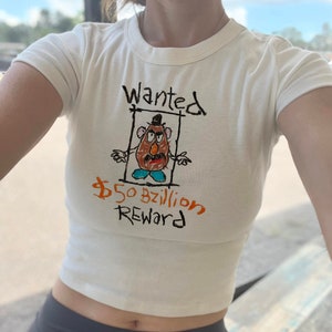 May include: White crop top with a hand-drawn image of Mr. Potato Head with the text "Wanted" and "$50bzillion Reward".