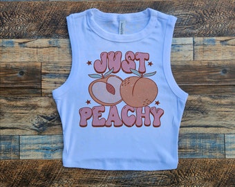 May include: White sleeveless crop top with a peach graphic and the text "Just Peachy" in pink and orange letters.